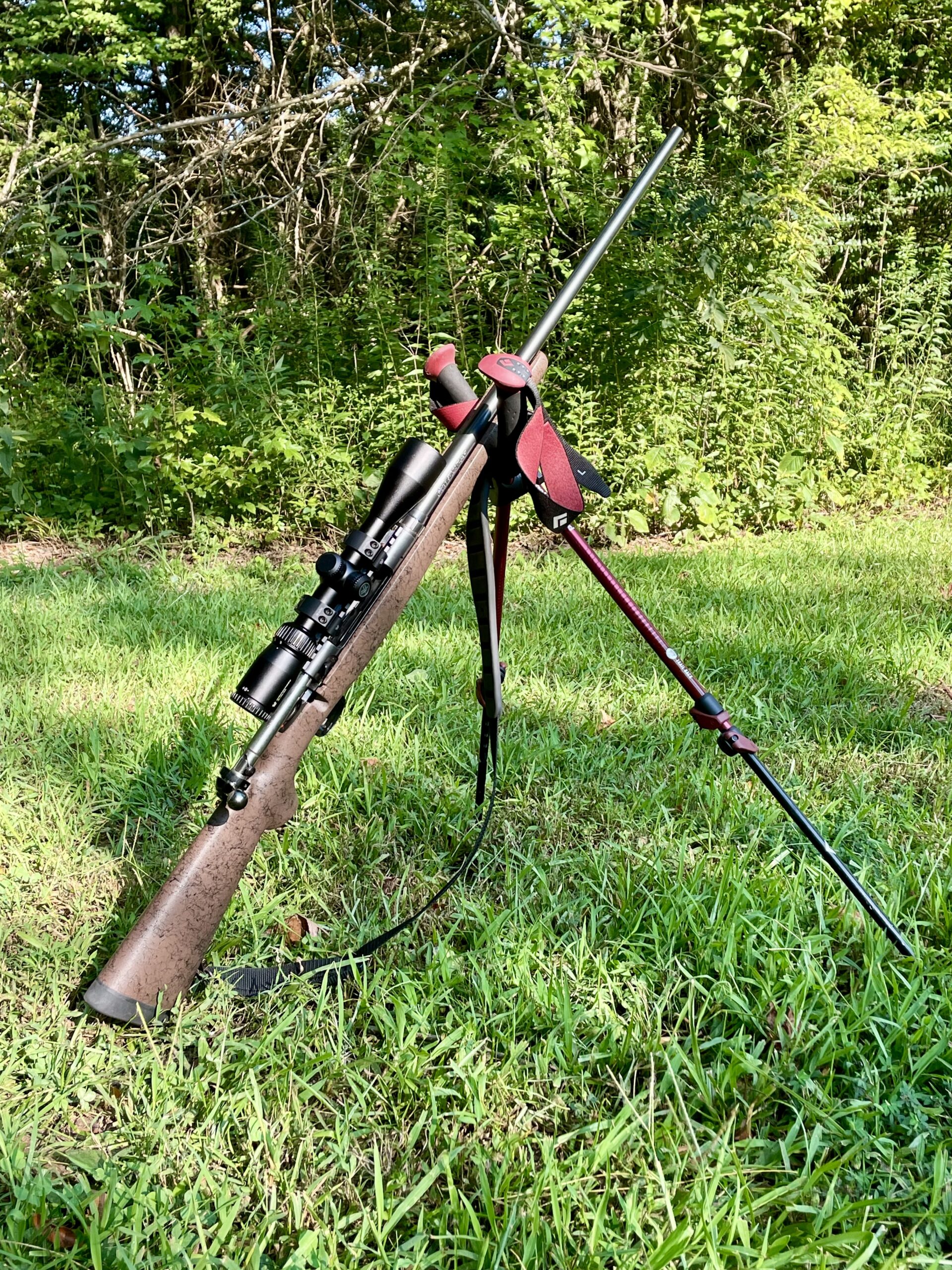 Image depicts bolt action rifle on crossed trekking poles.